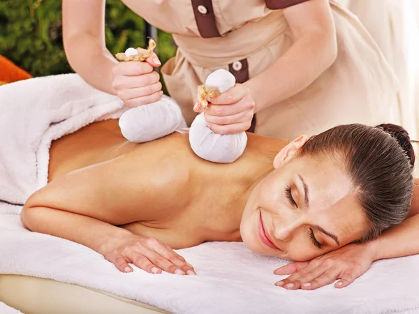 Woman getting herbal ball massage treatments .