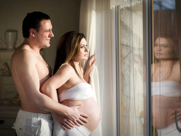 Pregnant wife and husband near window