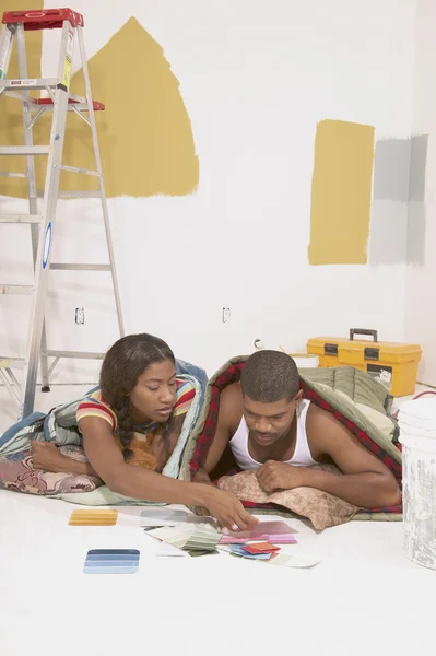 Couple looking at paint samples in sleeping bags