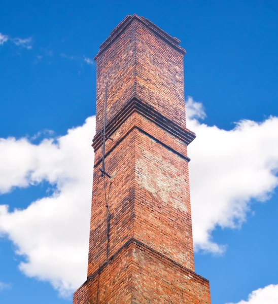 Close up brick chimney on the roof with cloudy blue sky backgrou